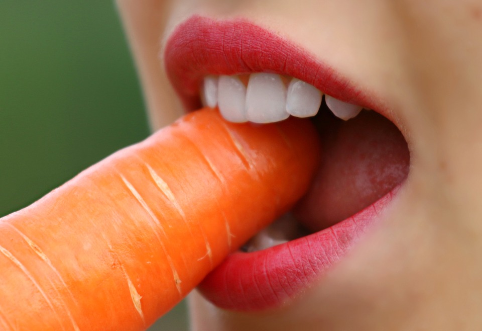 woman biting into a carrot